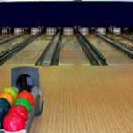 A bowling lane with multicoloured bowling balls.