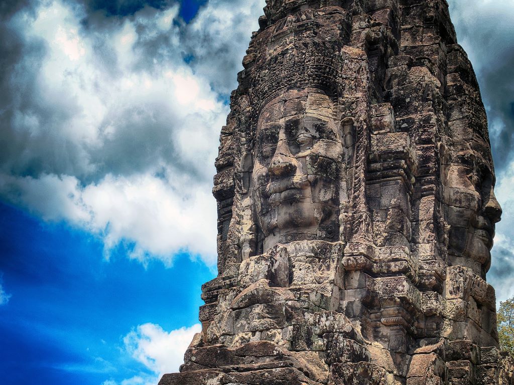 A view of a ancient monument with a face carved into it against a blue sky.