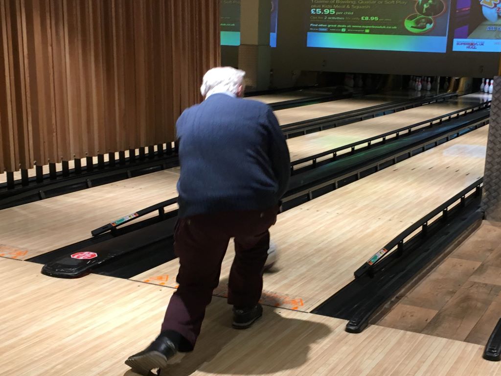 A man bowling on a ten pin bowling lane.