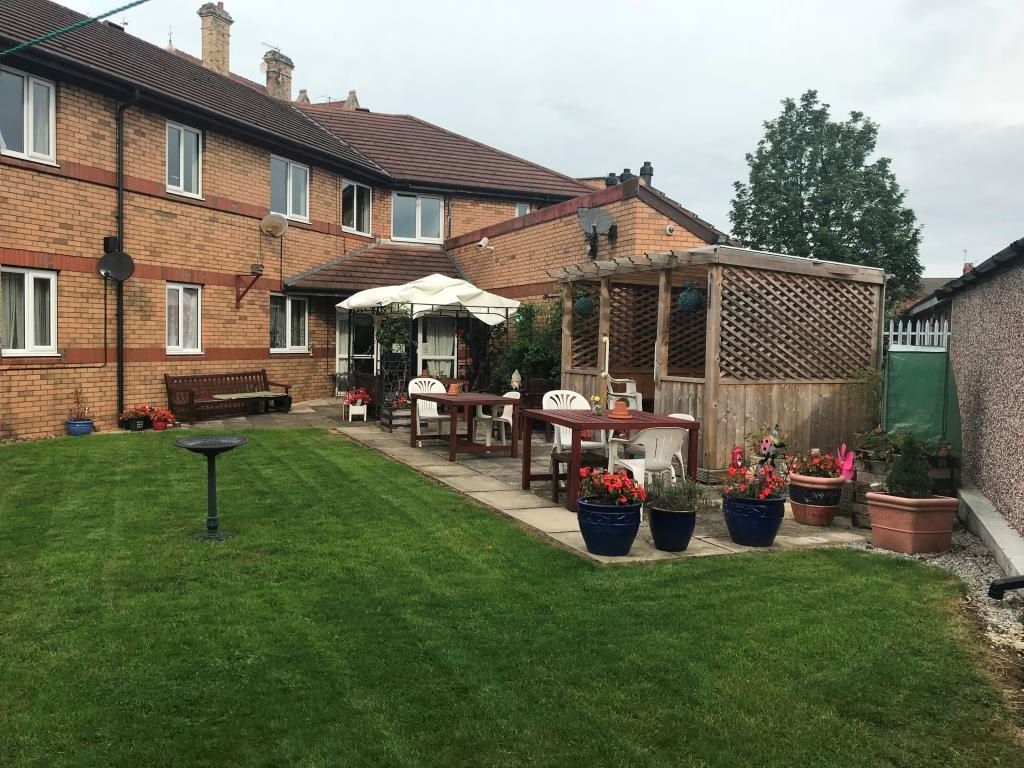 a garden with a lawn and potted plants and a covered seating area.