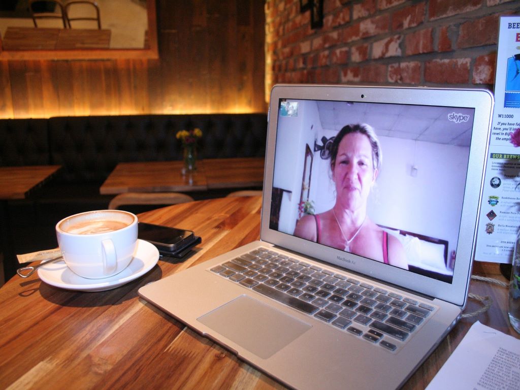A laptop on table beside a cup of coffee.