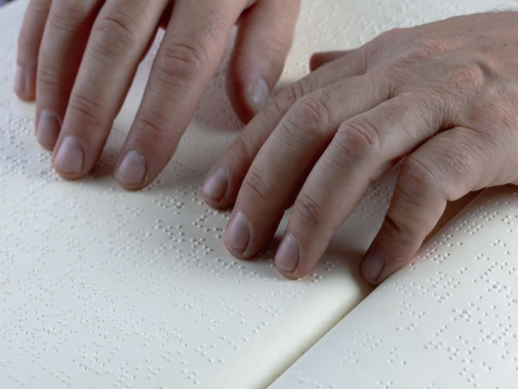 Two hands moving over braille writing.