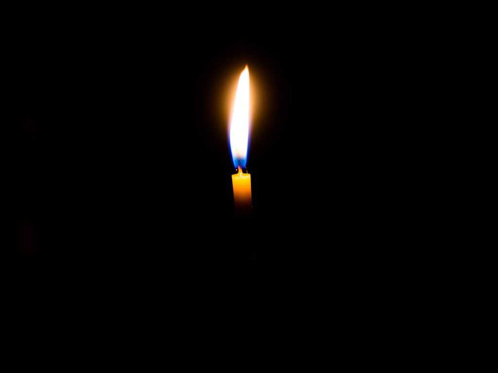 A candle flmae against a black background.