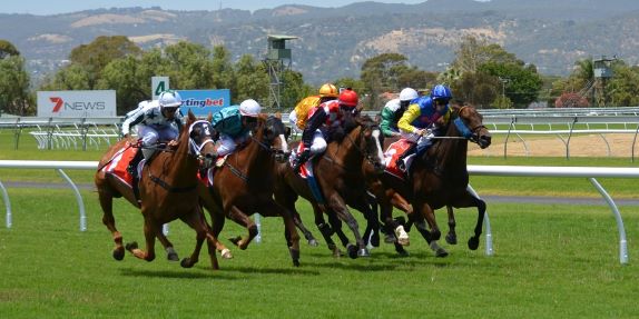 A group of race horses galloping around a race track
