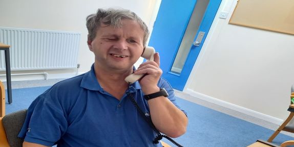 A smiling man making a telephone call