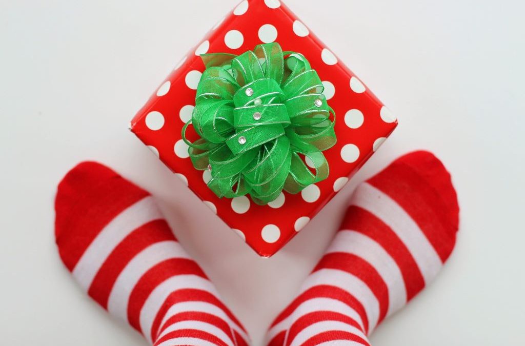 A pair of feet wearing red and white striped socks either side of a gift wrapped present.