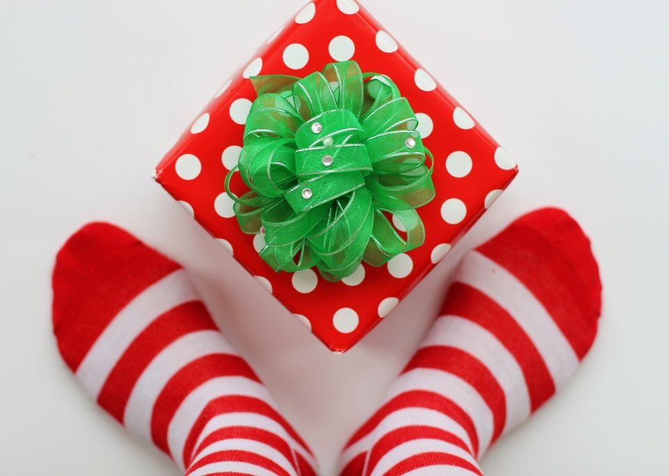 A pair of feet wearing red and white striped socks either side of a gift wrapped present.